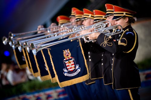 穿制服的人使用带有蓝色和黄色国旗的小号乐器 · 免费素材图片