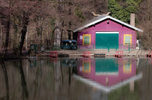 粉红色彩绘房子附近的平静水体 · 免费素材图片