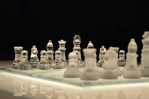 透明玻璃和白棋子在黑色背景上的白色国际象棋棋盘 · 免费素材图片