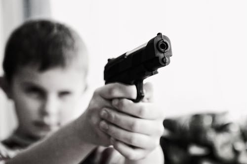 一个男孩瞄准玩具枪选择性聚焦摄影的灰度照片 · 免费素材图片