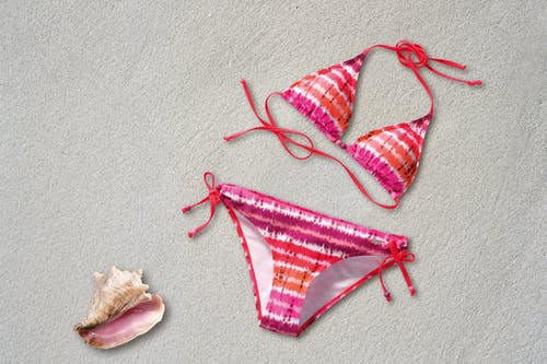 橙色粉红色白色条纹比基尼壳在沙滩上 · 免费素材图片