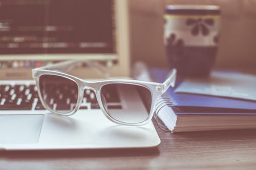 灰色便携式计算机顶部的透明镜框太阳镜 · 免费素材图片