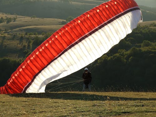 男子在地上用红色的黑色和白色降落伞 · 免费素材图片