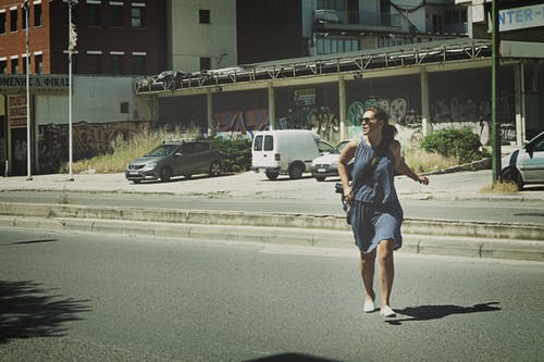 女人穿着灰色背心在沥青路面上行走 · 免费素材图片