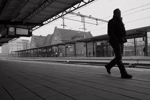 人在火车平台上行走的灰度照片 · 免费素材图片