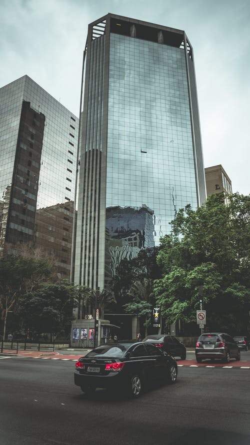 几辆车停在高层建筑附近 · 免费素材图片