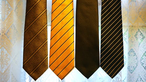 灰色纺织品上的四个拼色领带 · 免费素材图片