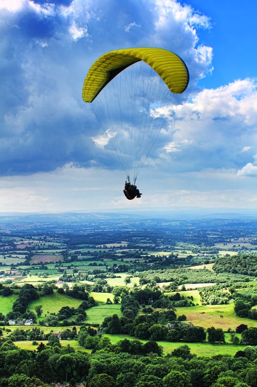 在多云的天空下滑翔伞的人 · 免费素材图片