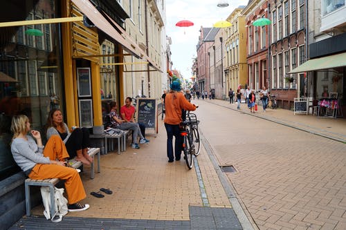 拿着自行车的人站立在大厦旁边 · 免费素材图片