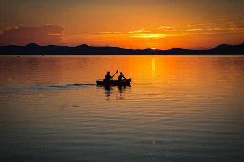 2人在日落期间在清澈的水中航行 · 免费素材图片