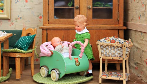 棕色的头发的女孩娃娃抱着婴儿的bassinet娃娃 · 免费素材图片
