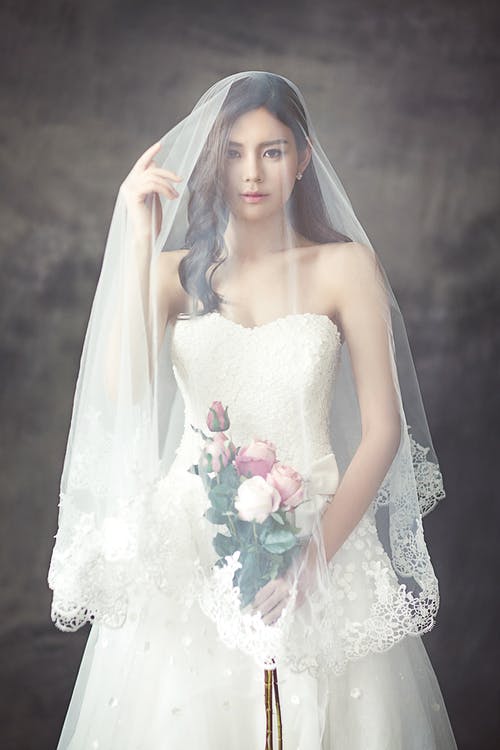白色露肩甜心婚纱的女人，玫瑰花束覆盖在白色面纱 · 免费素材图片