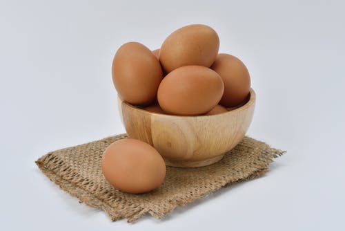 米色针织纺织品上的棕色木碗红皮蛋 · 免费素材图片