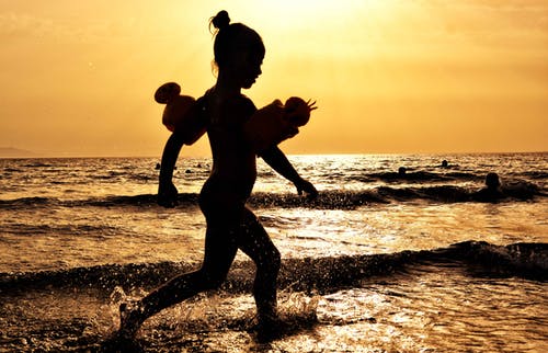 在黄金时段在海边跑步的女孩的身影 · 免费素材图片