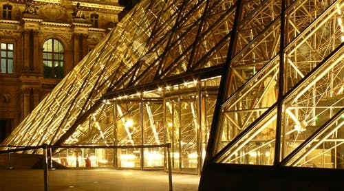 博物馆外的金属框架玻璃金字塔在夜间有黄灯 · 免费素材图片