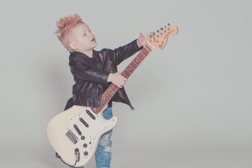 穿黑夹克的男孩抱着电吉他 · 免费素材图片