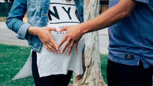 怀孕的妇女抱着她的肚子和旁边的男人在一起 · 免费素材图片