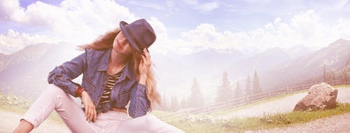 女人坐在地上，戴着黑色软呢帽，蓝色牛仔西装外套和白色紧身牛仔裤 · 免费素材图片