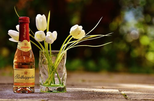 白色郁金香在透明玻璃旁边标记的bottl · 免费素材图片