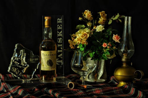 黄色和粉红色的玫瑰，在花瓶旁边的葡萄酒瓶特写摄影 · 免费素材图片