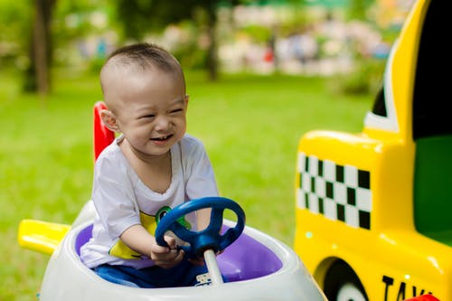 男孩骑乘骑玩具时微笑 · 免费素材图片