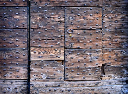 封闭的棕色木门与金属螺柱 · 免费素材图片