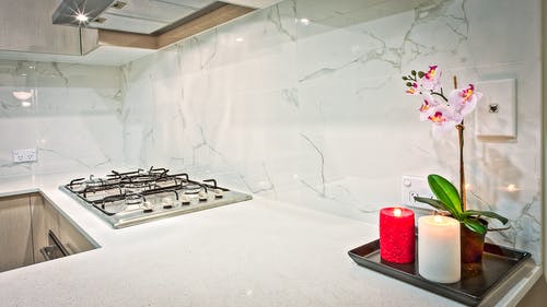 在厨房里的粉红色兰花花旁边的两个浅红色和白色支柱蜡烛 · 免费素材图片