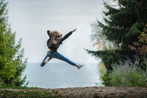 女人跳穿绿色背包 · 免费素材图片