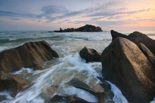 黄金时段时间流逝照片期间，海浪猛撞在棕色巨石上 · 免费素材图片