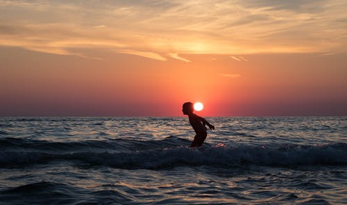 在日落期间被水包围的人的剪影 · 免费素材图片