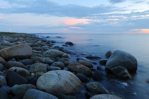 在日落期间对天空的海滩上的鹅卵石 · 免费素材图片