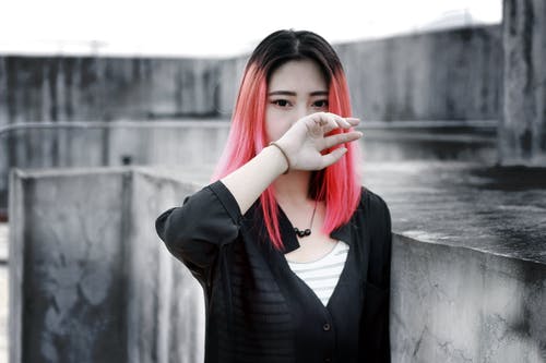 粉红色头发的女人standind混凝土墙附近 · 免费素材图片