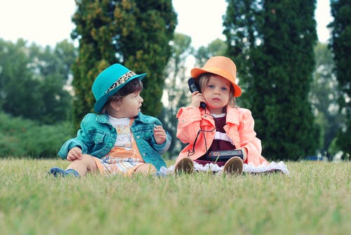 两个小孩坐在草地上 · 免费素材图片