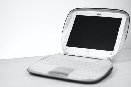 白色表面上的黑色屏幕上的白色苹果笔记本电脑 · 免费素材图片