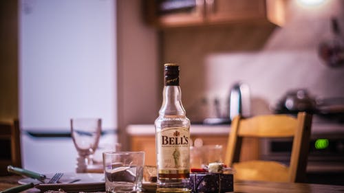 贝尔的威士忌酒瓶在桌上的草旁边 · 免费素材图片