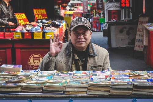 棕色外套在书前的人 · 免费素材图片