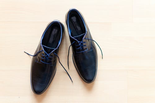 一双黑色皮革德比鞋放在棕色表面 · 免费素材图片