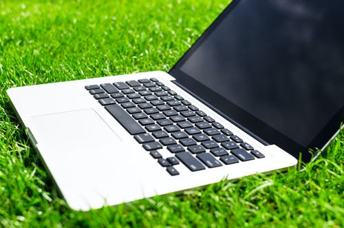 Macbook Pro在草地上具有关闭的屏幕 · 免费素材图片