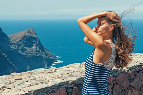 黑色和蓝色的条纹顶部，站在墙前的女人 · 免费素材图片