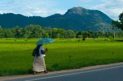 白色的裙子，走在路上拿着蓝绿色伞的女人 · 免费素材图片