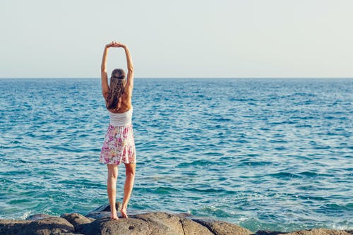 女人站在海边的岩石上 · 免费素材图片