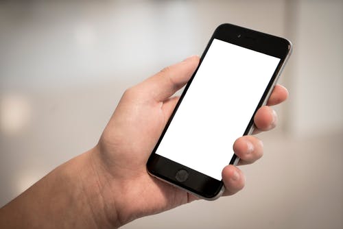 拿着iphone的人的选择性聚焦摄影显示白色屏幕 · 免费素材图片