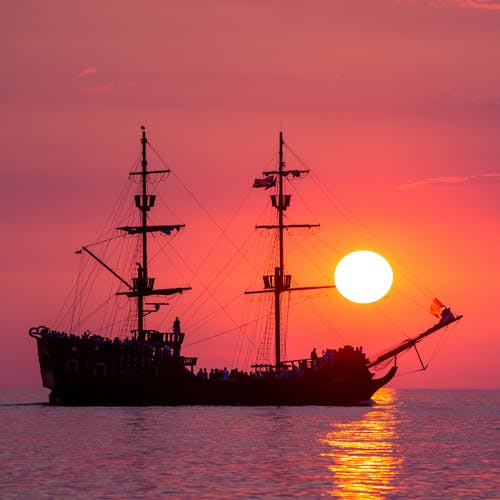 黄金时段在海上航行的海盗船的剪影 · 免费素材图片