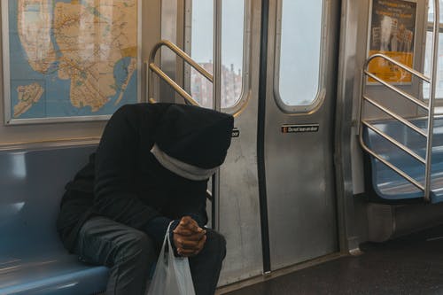 坐在火车长椅上的黑色连帽衫的人 · 免费素材图片