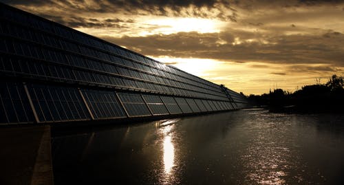 平静的水体附近的黑色太阳能电池板 · 免费素材图片