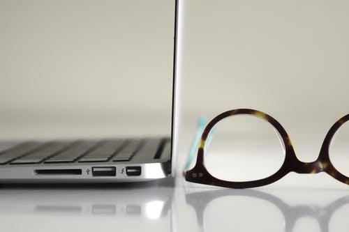 便携式计算机旁边的黑色镜框眼镜 · 免费素材图片