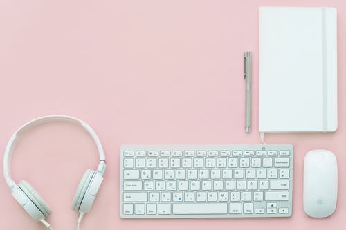 粉色表面上的apple Compact键盘，魔术鼠标和有线耳机 · 免费素材图片