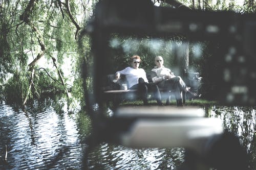 两名男子坐在长凳上的选择性聚焦摄影 · 免费素材图片