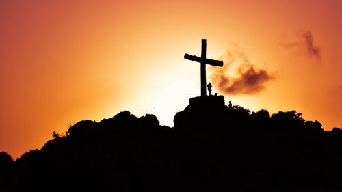 人类站在山上的耶稣受难像旁边 · 免费素材图片