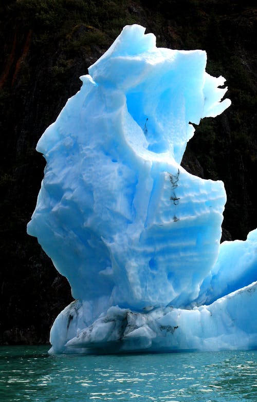 冰山漂浮在悬崖附近的水 · 免费素材图片